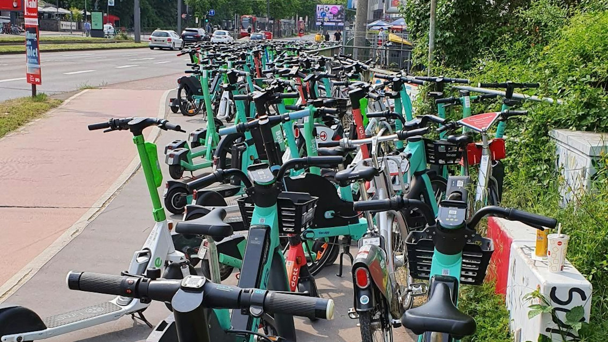 Hunderte E-Scooter und Leih-Fahrräder stehen während eines Heimspiels des 1. FC Köln an der Aachener Straße. Hinter der Brücke über den Militärring ist das Abstellen durch die Apps der Anbieter untersagt.