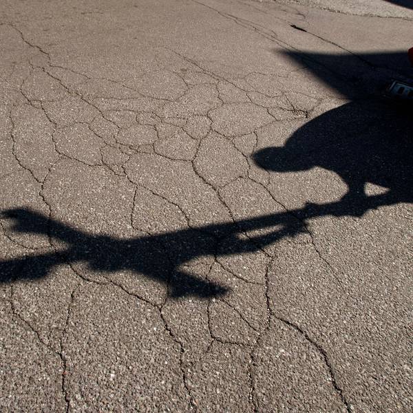 Der Schatten eines Priesters mit einem Kreuz ist auf einem Asphalt zu sehen.