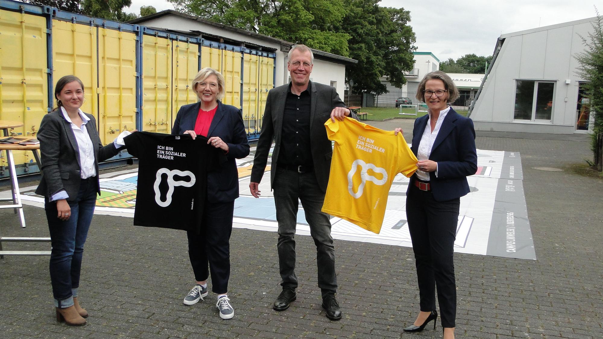 Drei Frauen und ein Mann halten T-Shirts in die Luft.