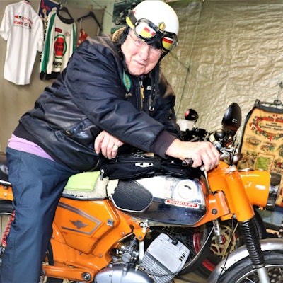 Der ehemalige Rennfahrer sitzt in seiner Garage auf seinem Motorrad.