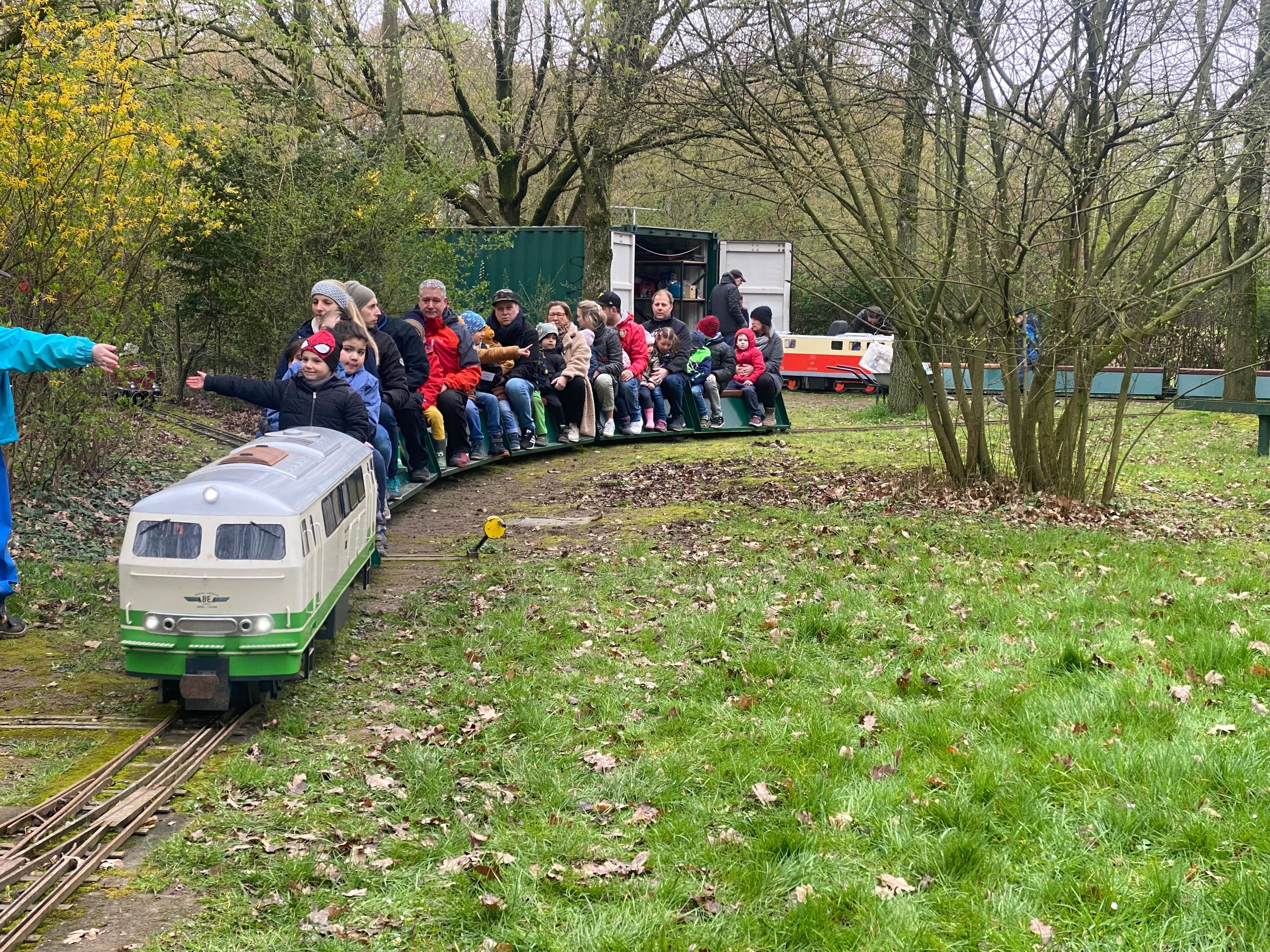 Dampfbahn-Lokomotive fährt mit Passagieren auf den Anhängern durch den Stadtpark