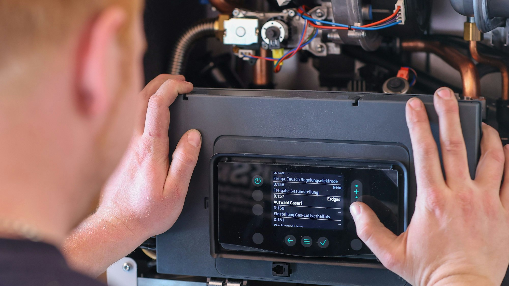 Ein Mitarbeiter einer Sanitär- und Heizungsbaufirma installiert eine moderne Gasbrennwerttherme.