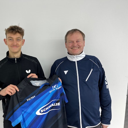 Zwei Männer stehen nebeneinander. Der Jüngere hält sein neues Trikot des Tischtennis-Bundesligisten aus Bergneustadt in den Händen.