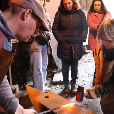 Ein Mädchen versucht sich mit einem Schmiedehammer.