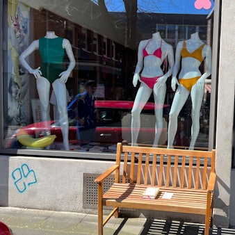 Die Sitzbank steht vor dem Geschäft.