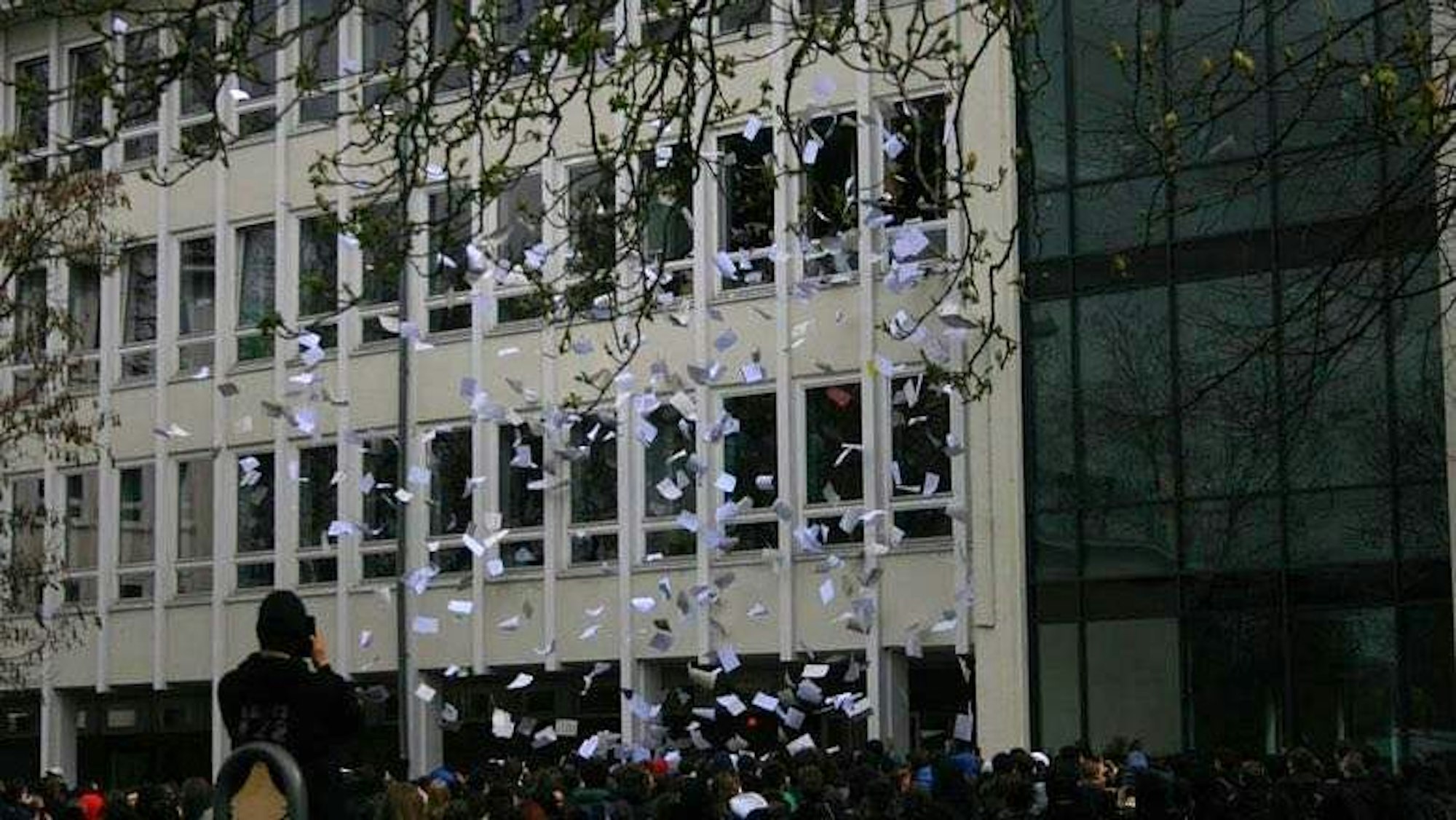 Abigag 2023: Hunderte weiße Blätter fliegen aus Fenstern des Schulgebäudes des Rhein-Gymnasiums in Köln-Mülheim.