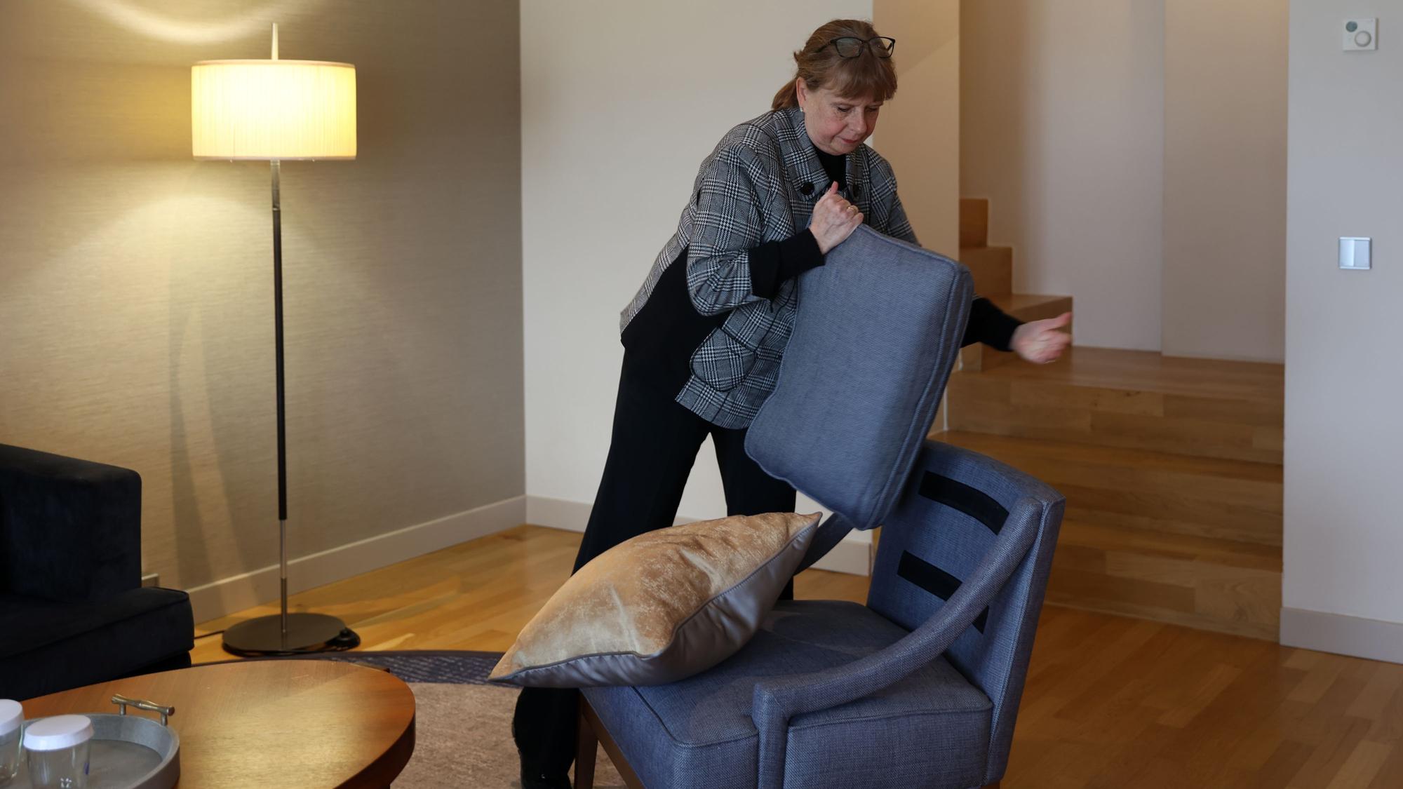 Andrea Pilz hat das Sitzkissen von einem Sessel abgenommen und schüttelt es aus.