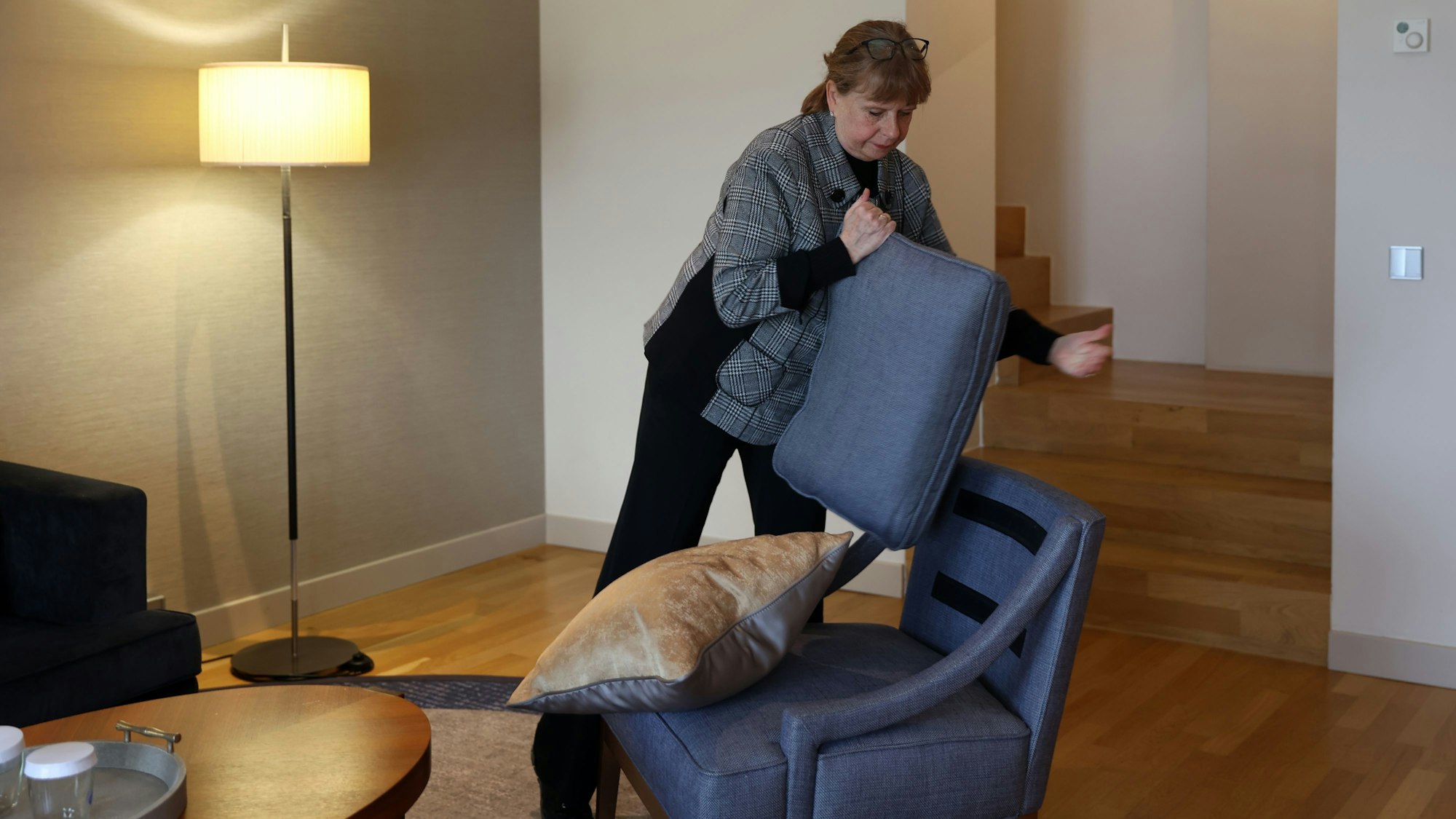 Andrea Pilz hat das Sitzkissen von einem Sessel abgenommen und schüttelt es aus.