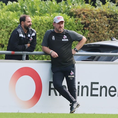 FC-Nachwuchstrainer Stefan Ruthenbeck und Chef-Coach Steffen Baumgart stehen am Geißbockheim zusammen.