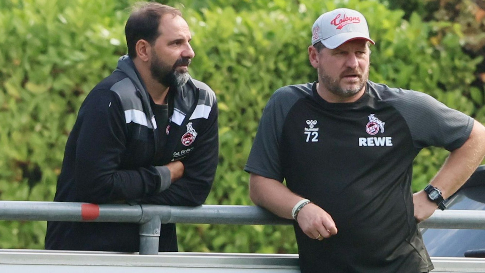 FC-Nachwuchstrainer Stefan Ruthenbeck und Chef-Coach Steffen Baumgart stehen am Geißbockheim zusammen.
