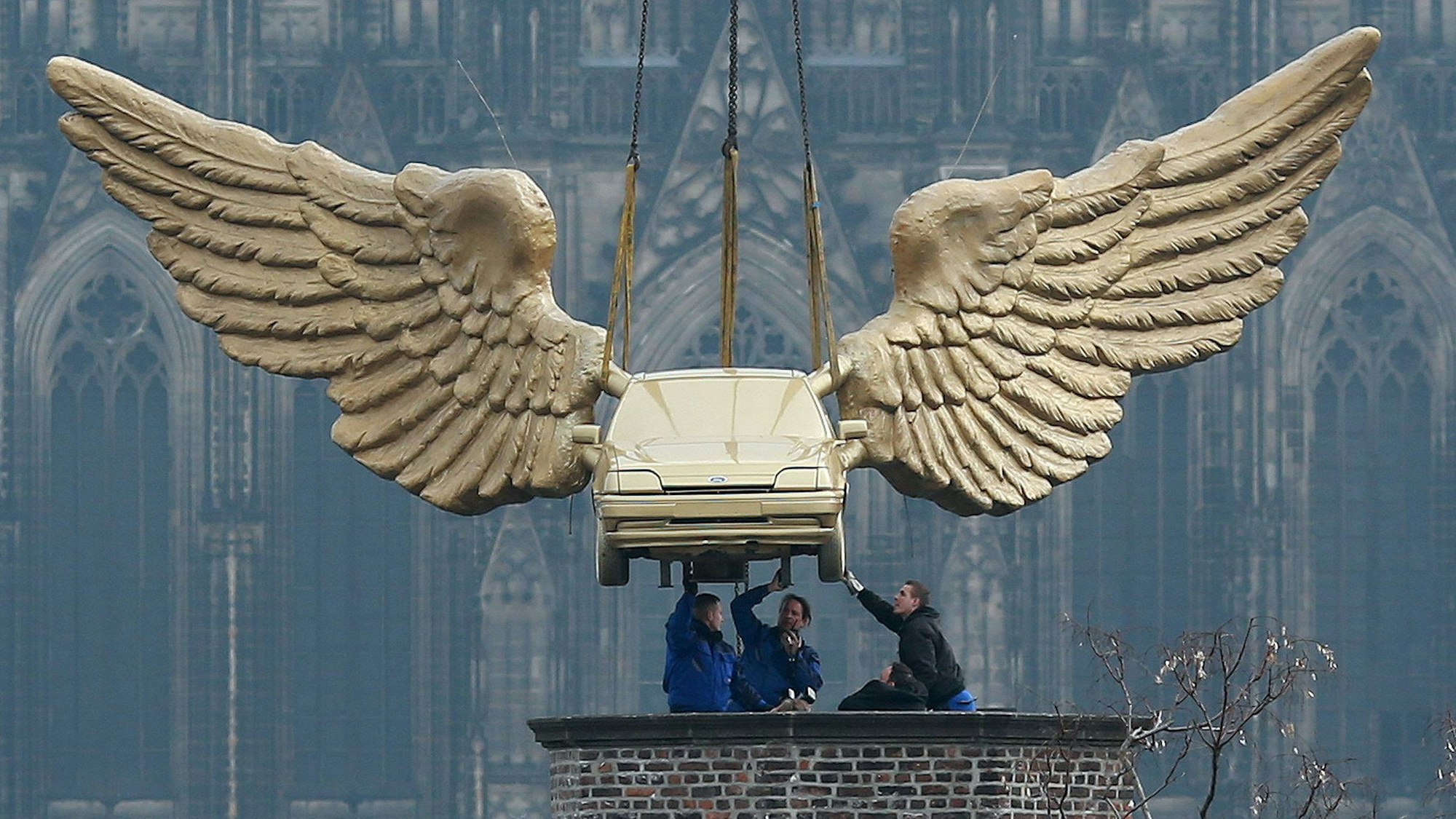 Das Flügelauto des Aktionskünstlers HA Schult hängt an einem Kran und wird auf den Turm des Kölnischen Stadtmuseums in Köln gesetzt.