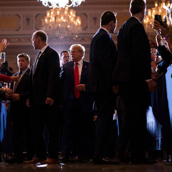 Es ist eine Menschenmenge zu sehen. Trump läuft durch die Mitte dieser.