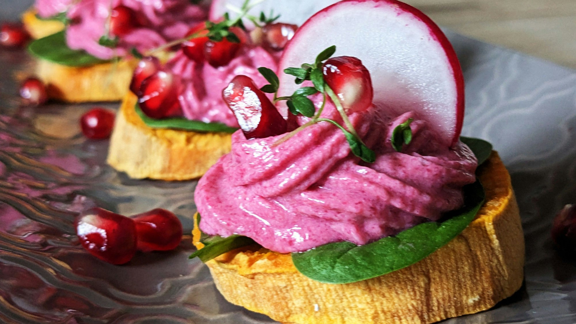 Auf einer Süßkartoffelscheibe ist ein Rote-Bete-Frischkäse-Türmchen aufgespritzt.