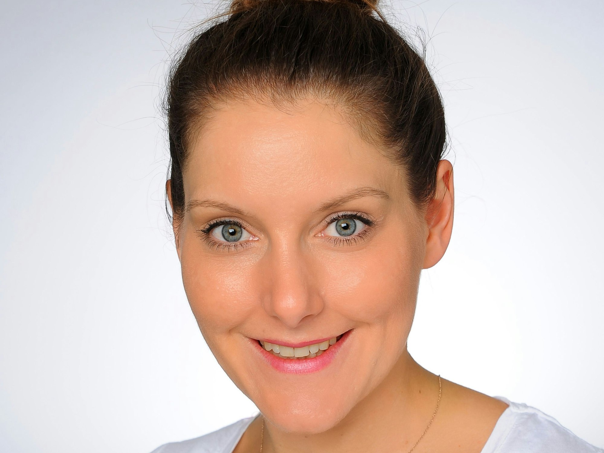 Mareike Brandt guckt für ein Porträtfoto in die Kamera. Sie trägt ein weißes T-Shirt und einen Dutt.