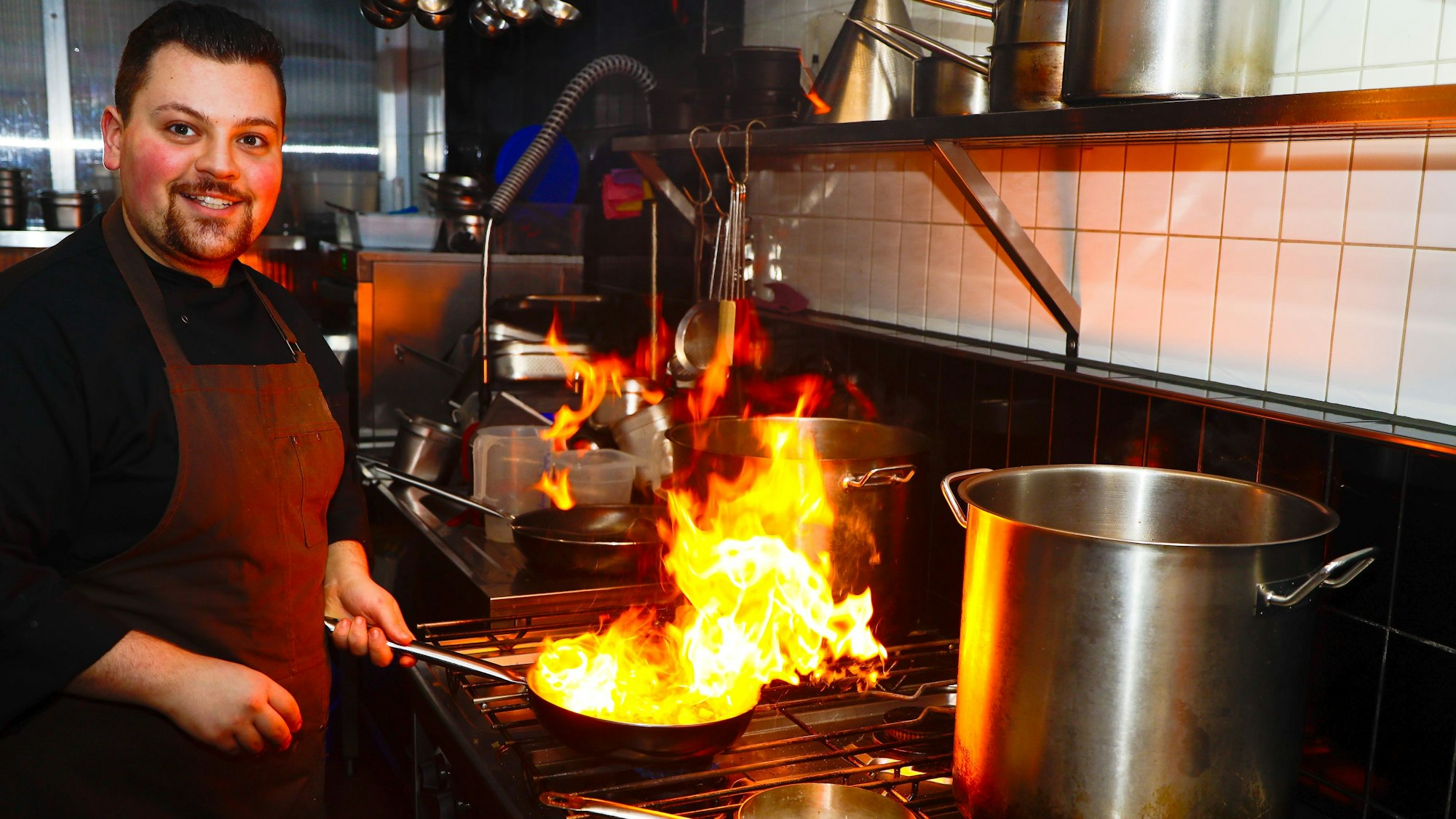 Koch Rosario beim Flambieren in der offenen Küche.