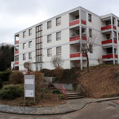 Das Seniorenzentrum Otterbach in Bad Münstereifel steht leicht erhöht. Auf einem Parkplatz rechts unten vor dem Gebäude parkt ein graues Auto. Links unten im Bild führt eine Straße entlang.