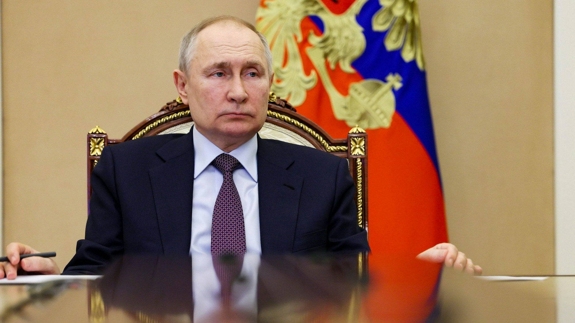 Der russische Präsident Wladimir Putin sitzt an einem Tisch im Kreml. Im Hintergrund ist die russische Flagge zu sehen.