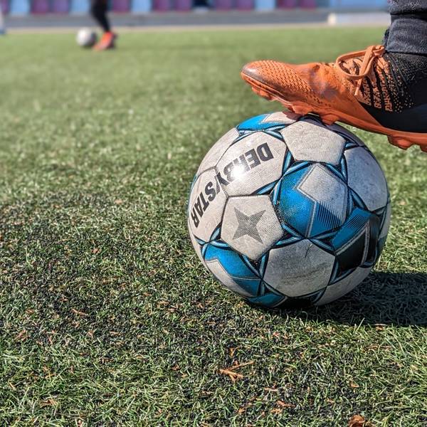 Das Bild zeigt einen Fußball auf dem durch Bengalos beschädigten Kunstrasenplatz.