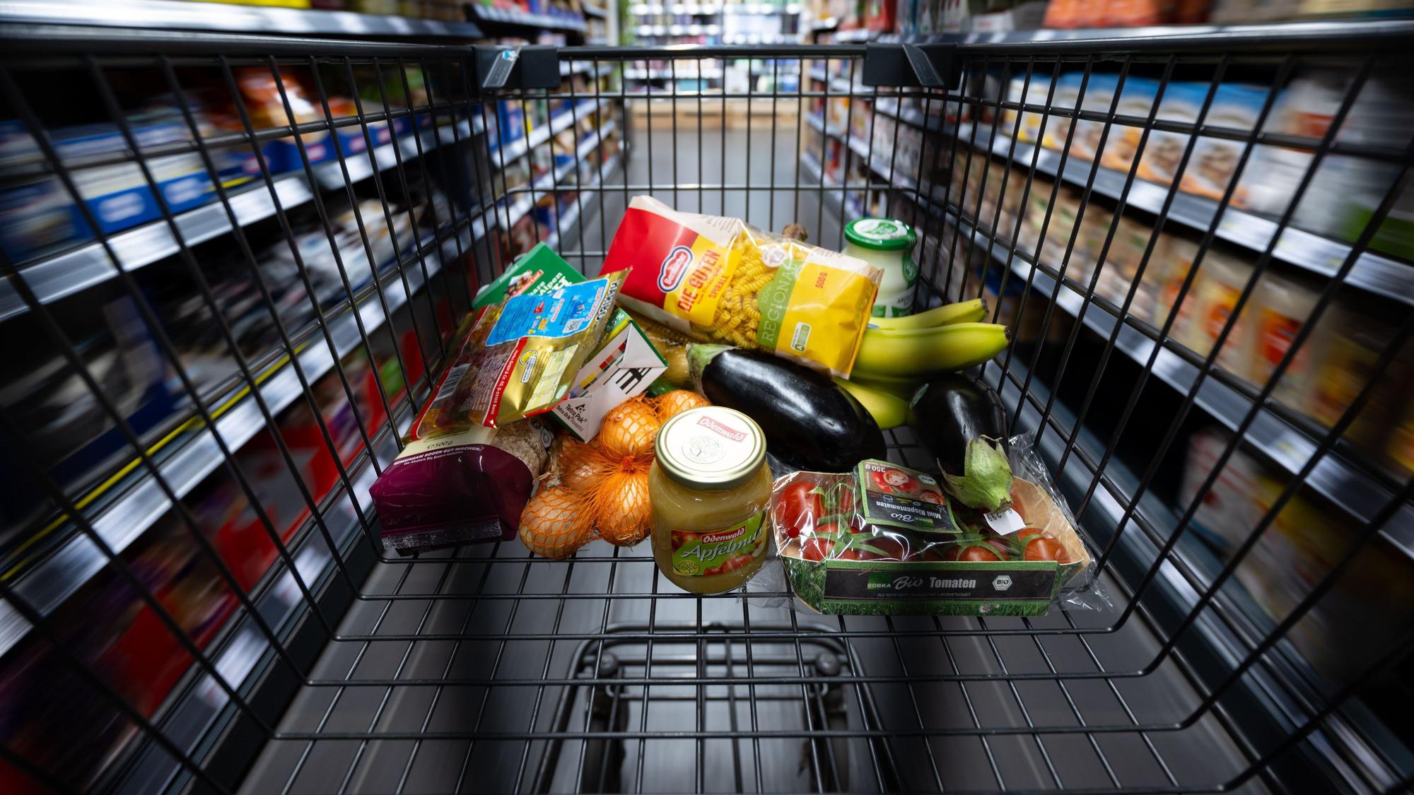 Verschiedene Lebensmittel liegen in einem Supermarkt in einem Einkaufswagen.