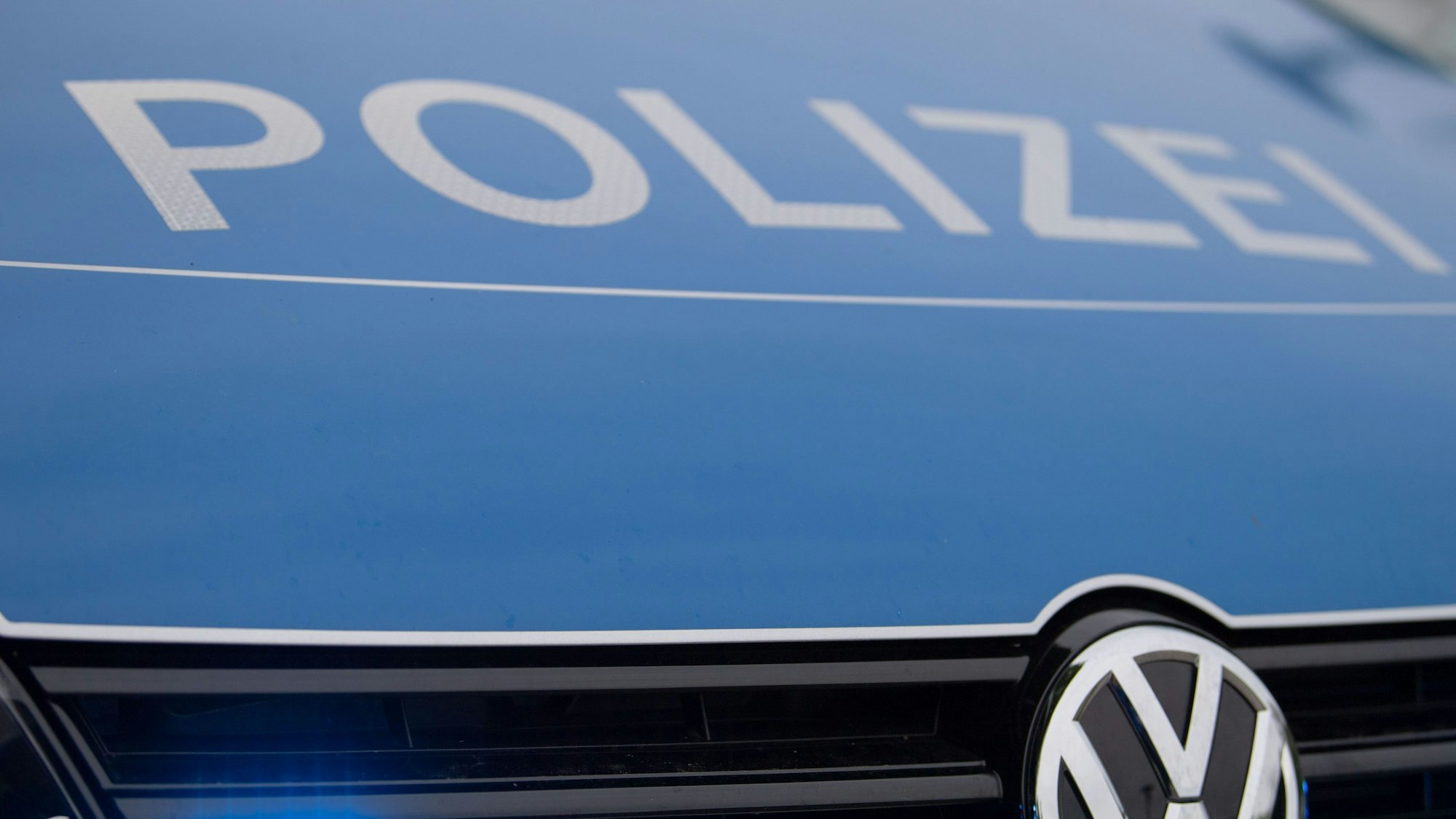 Ein Blaulicht leuchtet im Kühlergrill einer Polizeiautos.