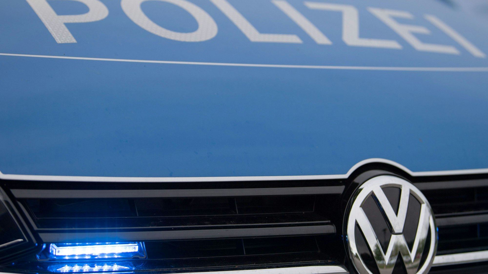 Ein Blaulicht leuchtet im Kühlergrill einer Polizeiautos.