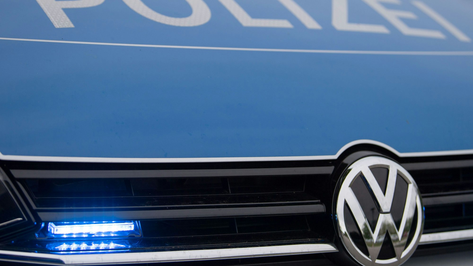 Ein Blaulicht leuchtet im Kühlergrill einer Polizeiautos.