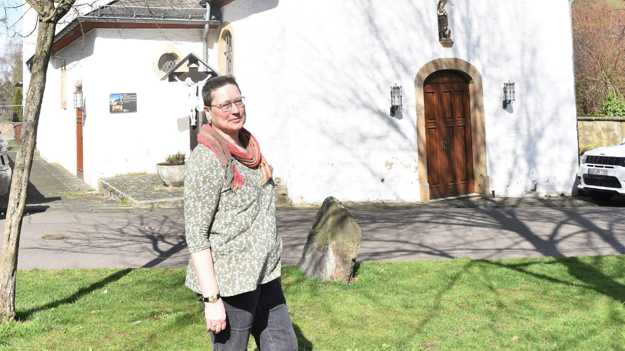 Eine Frau steht vor der kleinen Kirche in Eiserfey.