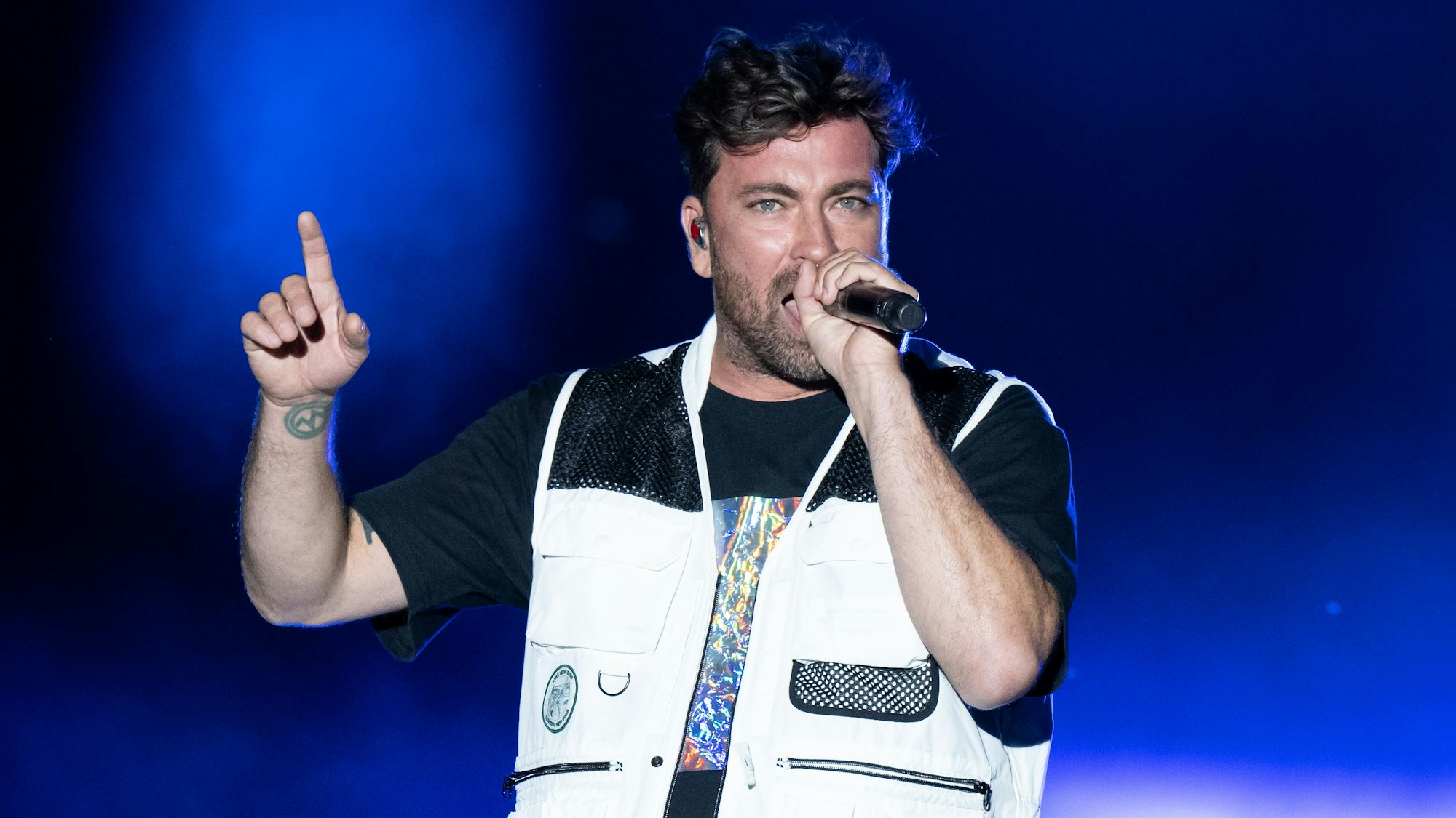 Rapper Marteria steht auf einer Bühne und hält sich ein Mikrofon vor den Mund.