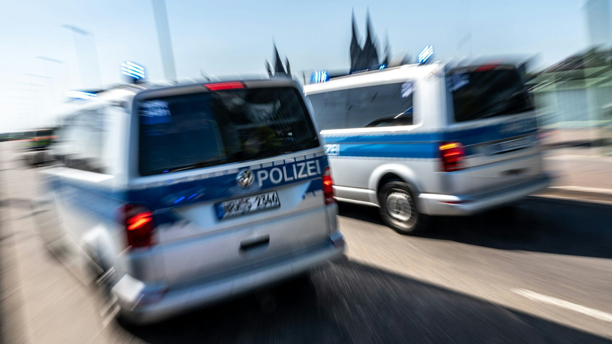 Zwei Polizeifahrzeuge auf der Deutzer Brücke mit dem Dom im Hintergrund