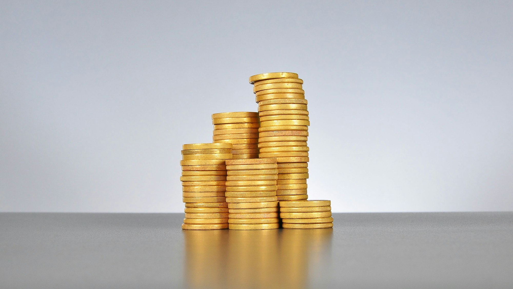 Einige aufgestapelte Goldmünzen auf einem Tisch.