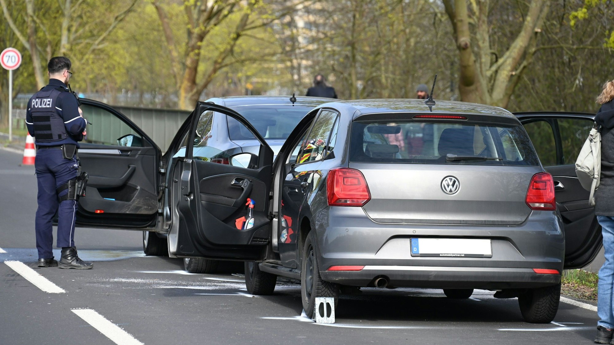 Zwei Autos stehen mit offenen Türen auf der Straße. Ein Polizist steht daneben.