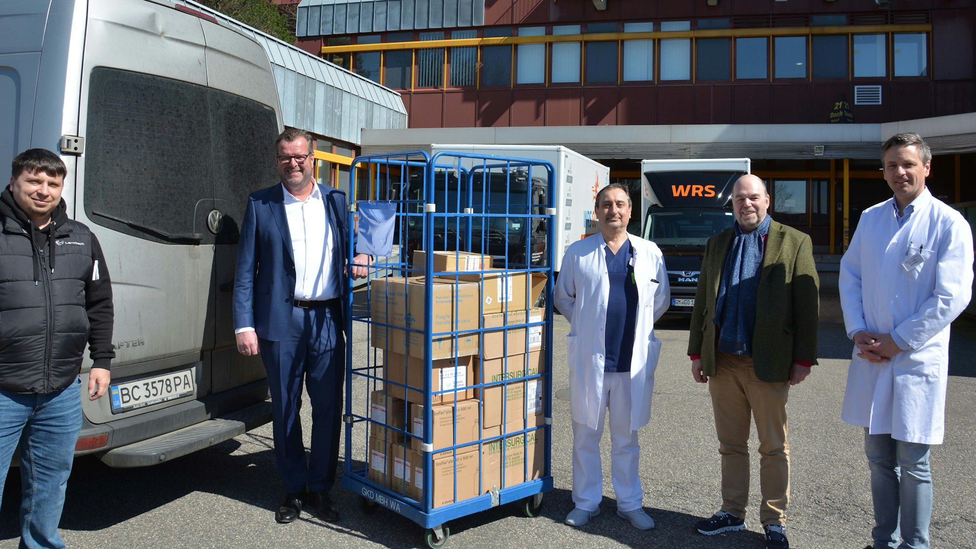 Fünf Männer stehen mit mehreren Kartons neben einem Lieferwagen.