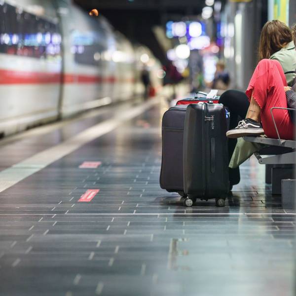 Eine Frau wartet am frühen Morgen mit ihrem Koffer im Frankfurter Hauptbahnhof.