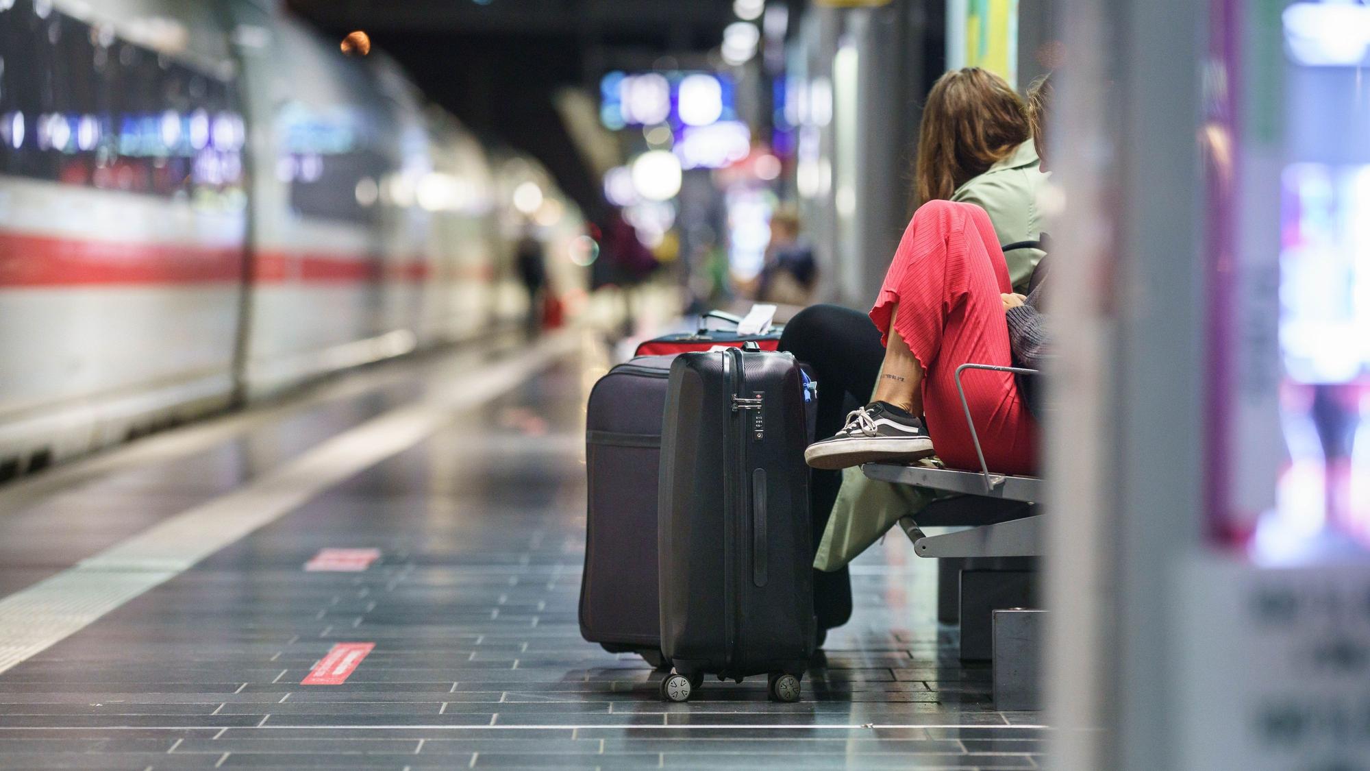 Eine Frau wartet am frühen Morgen mit ihrem Koffer im Frankfurter Hauptbahnhof.