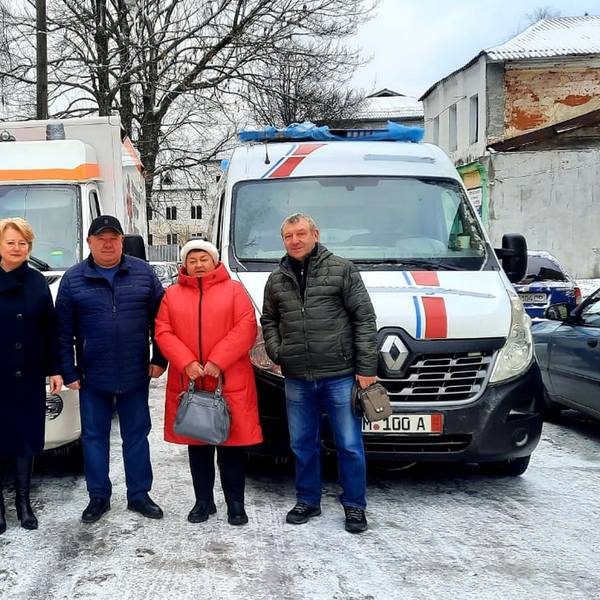 Drei Männer und zwei Frauen stehen vor zwei Rettungsfahrzeugen.