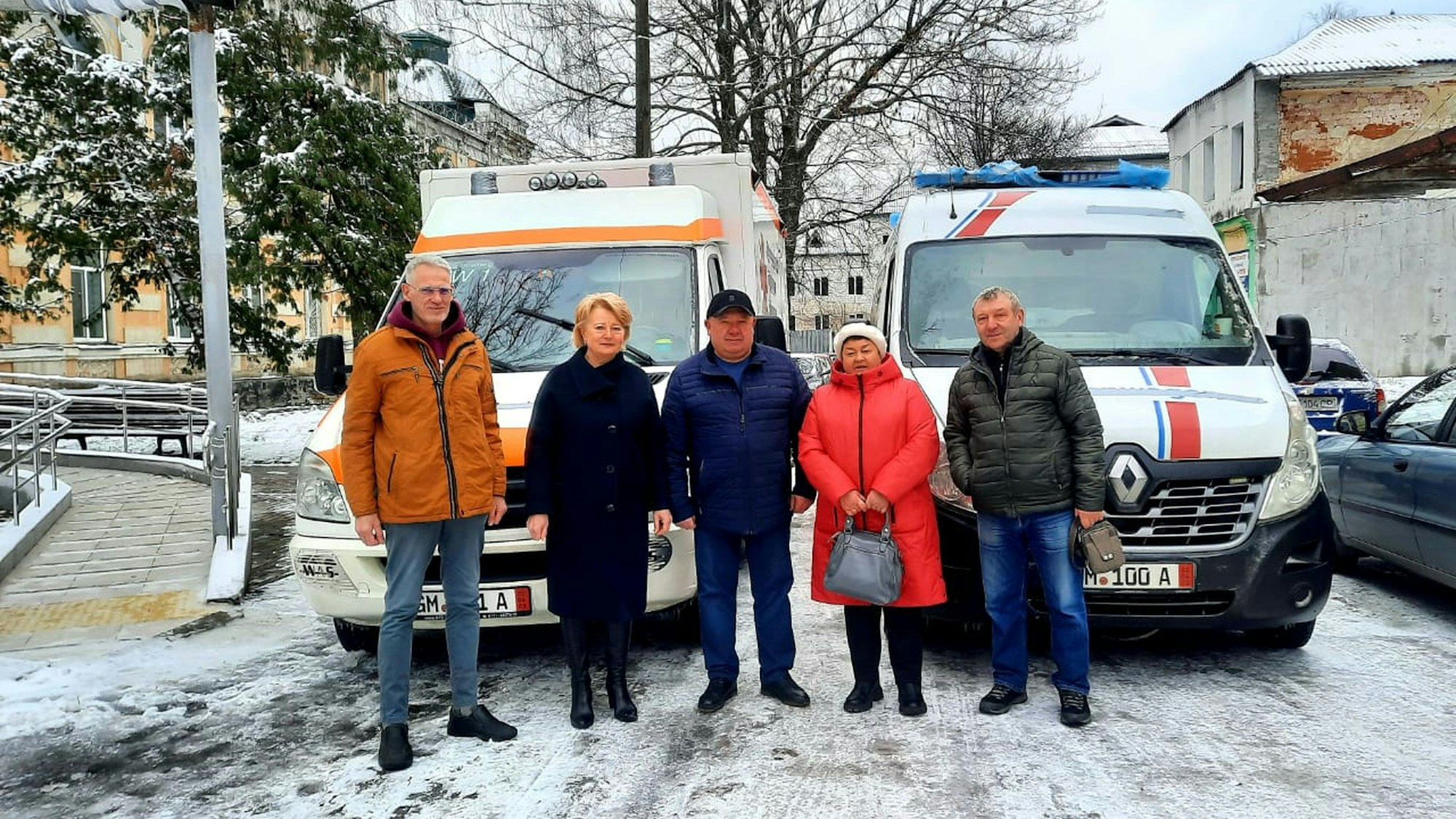 Drei Männer und zwei Frauen stehen vor zwei Rettungsfahrzeugen.