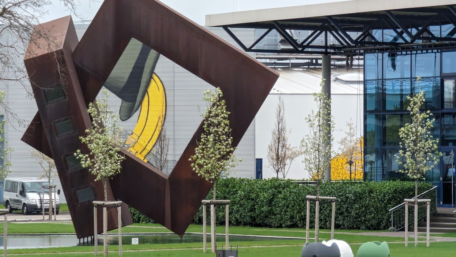 Eine Skulptur aus zwei großen, ineinander verschränkten Quadraten steht in einem Teich vor den Gebäudekomplexen des Euronova Campus in Hürth.