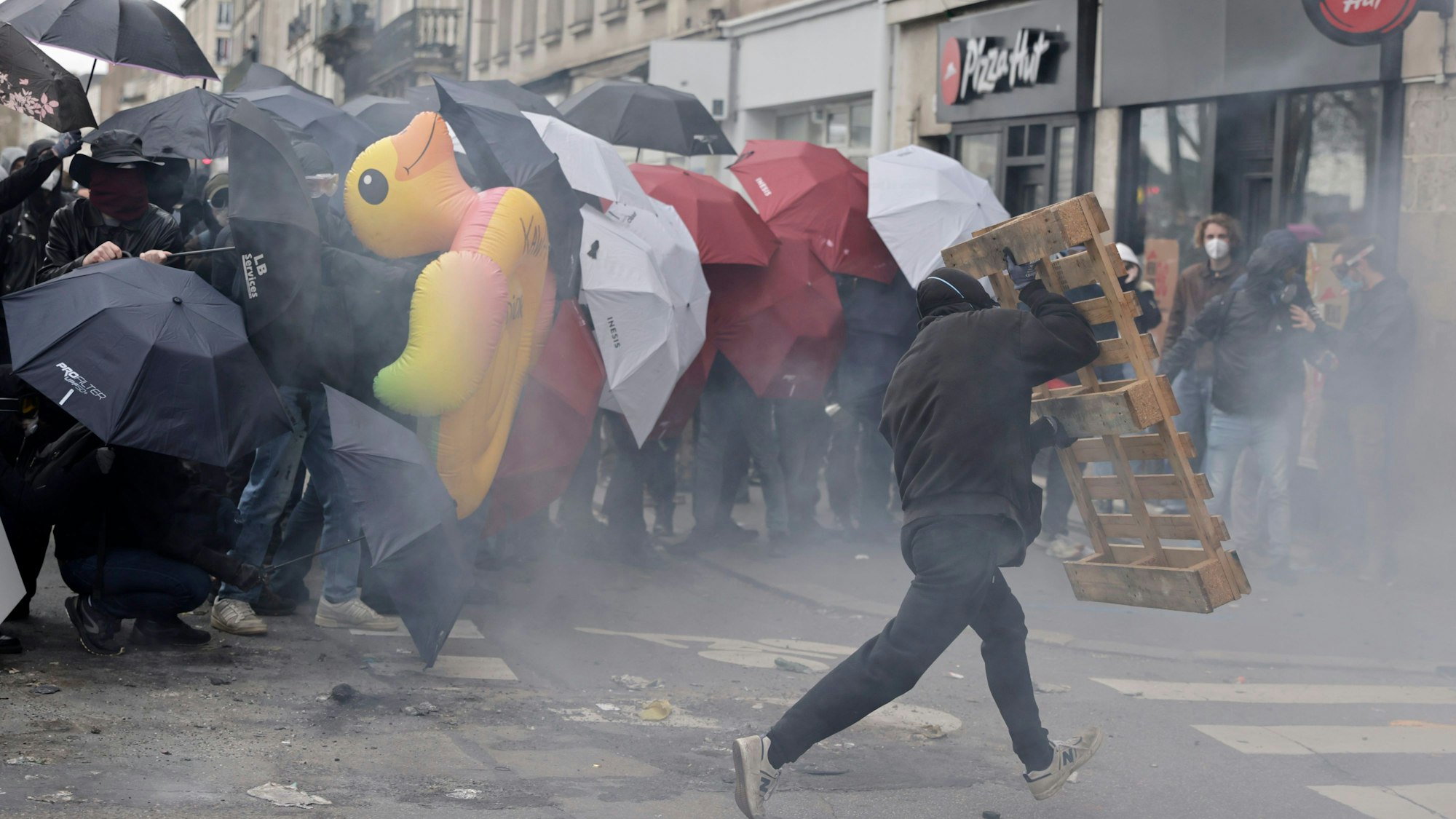 Demonstranten schützen sich mit Regenschirmen vor Tränengas.