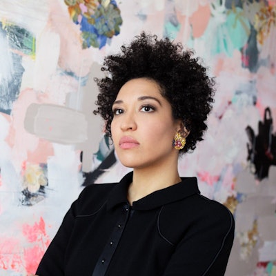 Julia Bullock steht vor einer bunten Tapete.