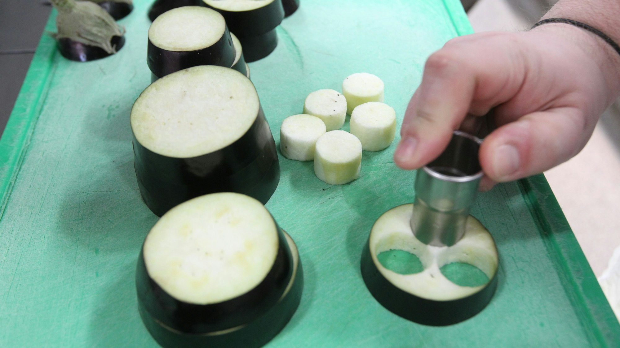 Aus Scheiben einer Aubergine werden kleine Kreise ausgestochen.