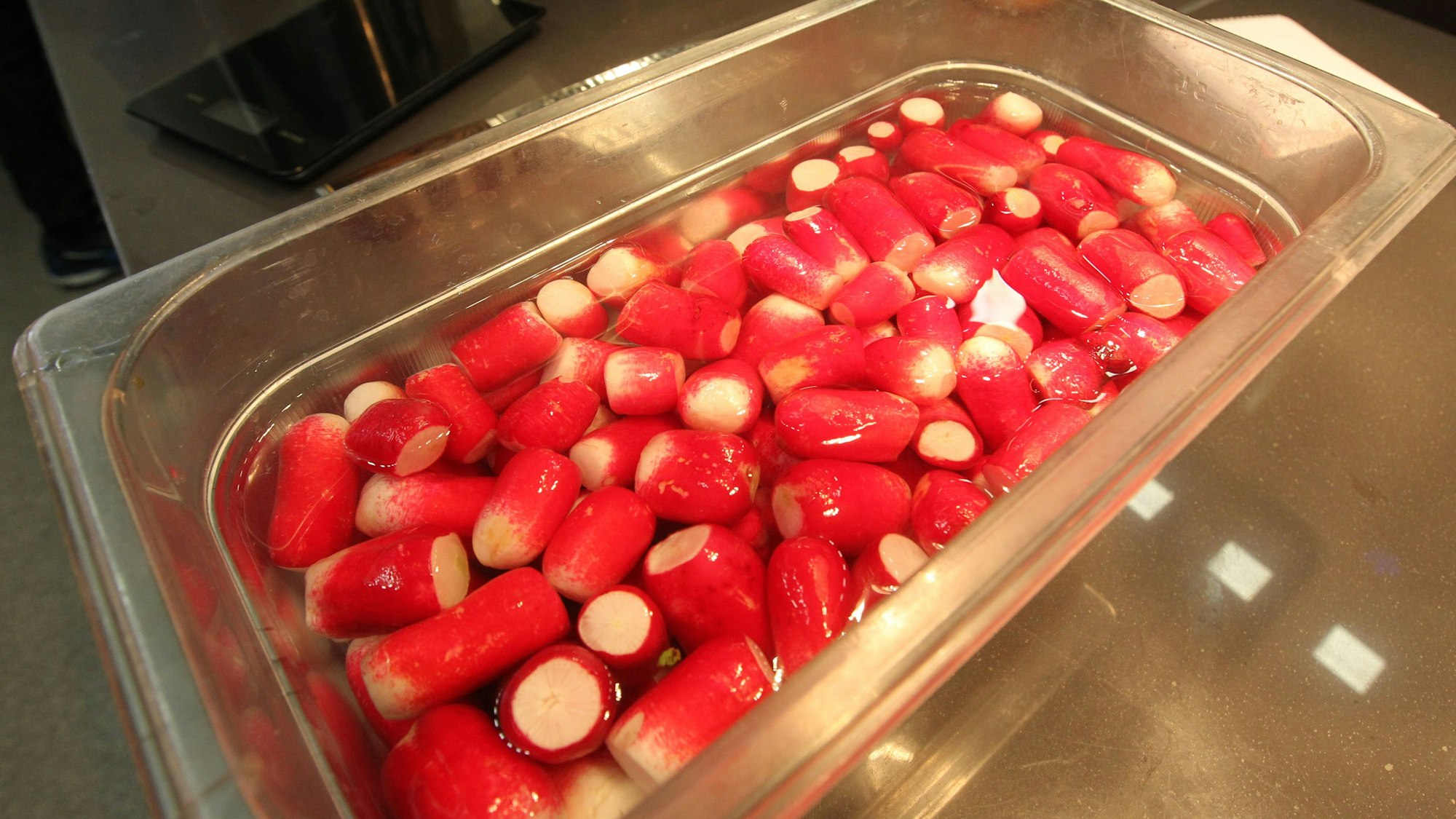 Radieschen liegen in einem Metallbehälter.