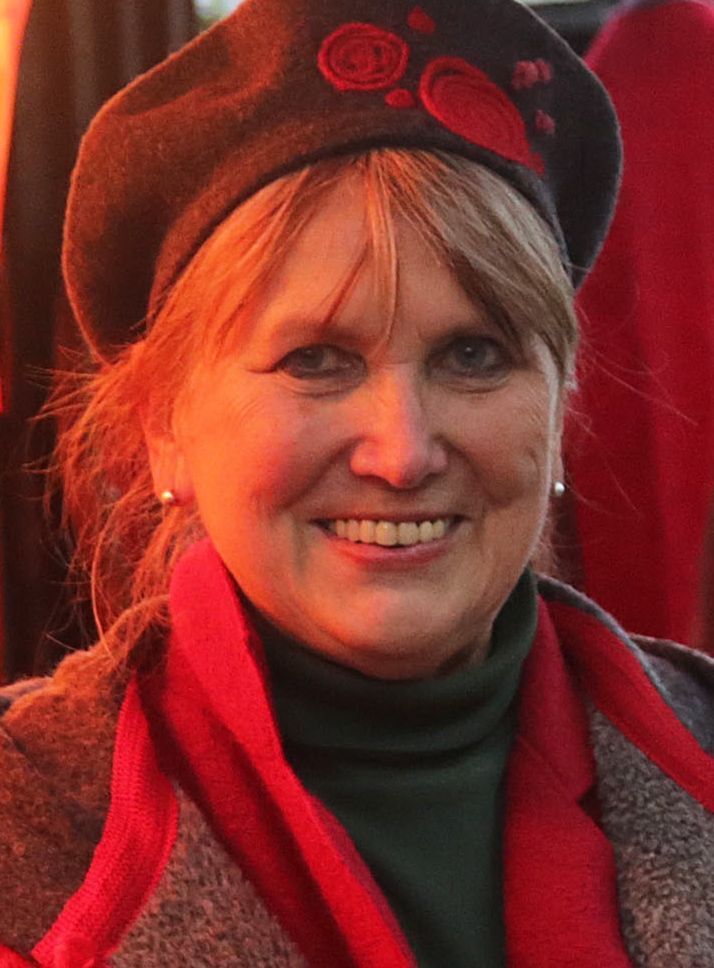 Eine Frau mit einem roten Hut auf dem Kopf lächelt.