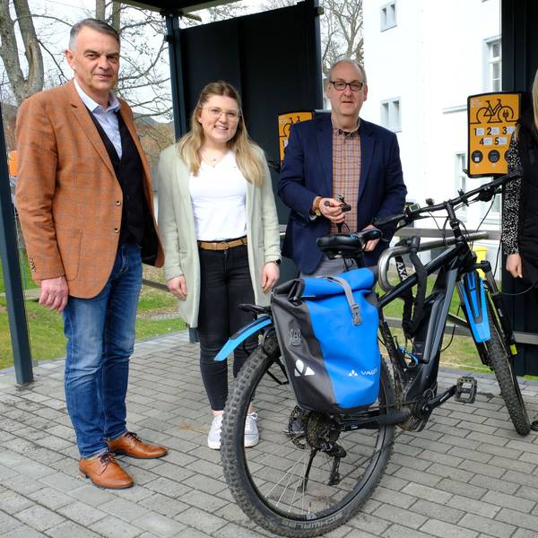 Zwei Männer und zwei Frauen stehen mit Fahrrädern an der E-Bike-Ladestation in Hellenthal.