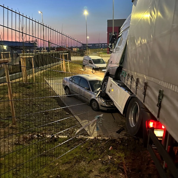 Ein Lastwagen steht mit der Zugmaschine auf einem demolierten Auto. Im Vordergrund ist ein durchbrochener Zaun zu sehen.