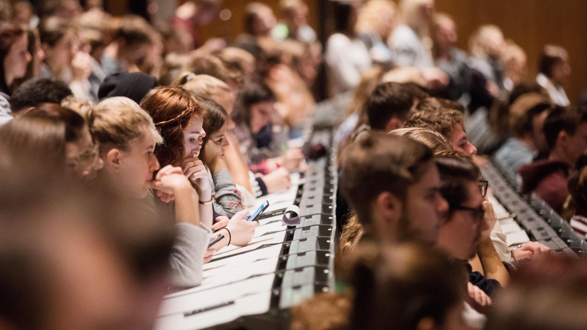 Studenten verfolgen im Hörsaal im Hauptgebäude der Kölner Universität die Erstsemesterbegrüßung