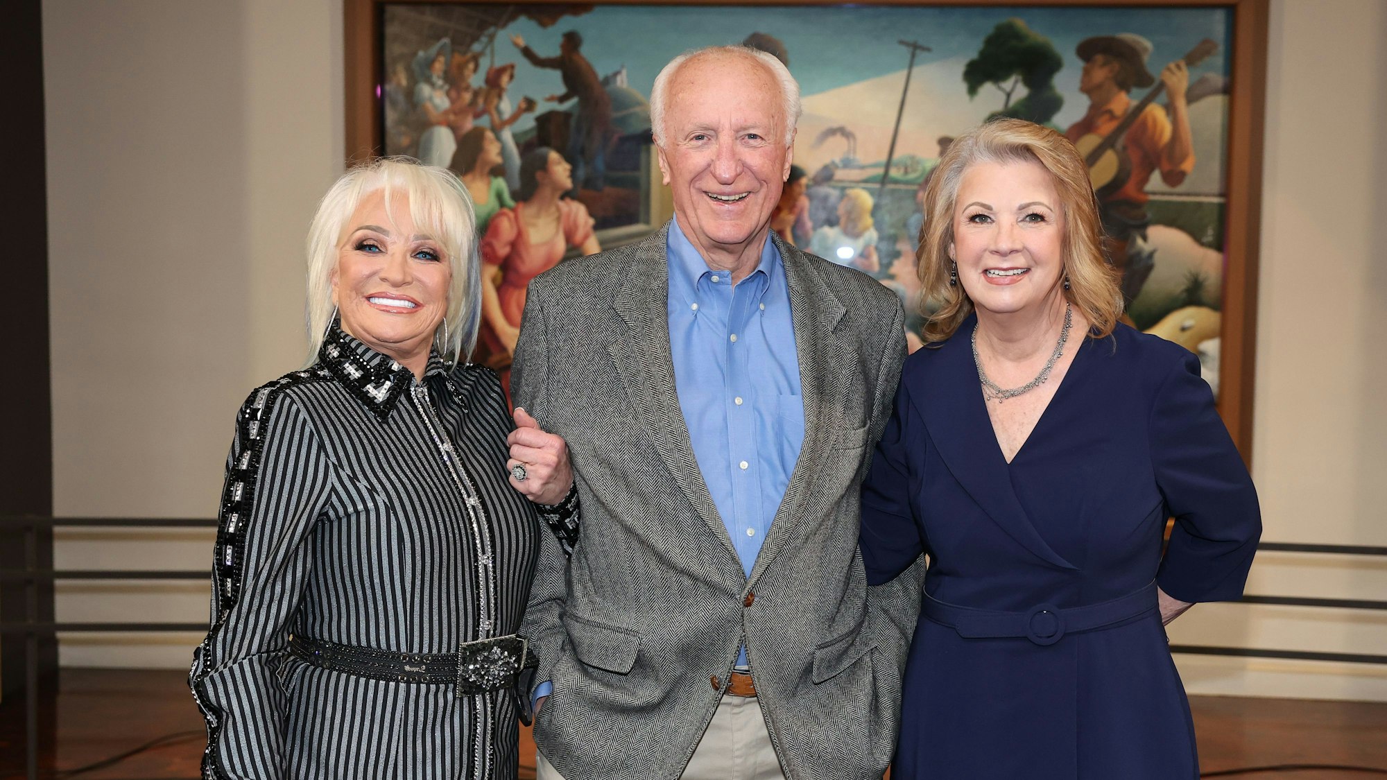 Tanya Tucker, Bob McDill und Patty Lovelesss posieren Arm in Arm bei einer Pressekonferenz.