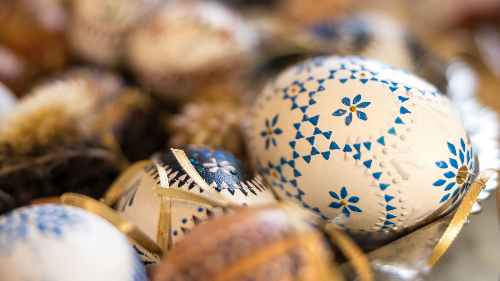 Mit Wachs bemalte Ostereier liegen auf einem Tisch.