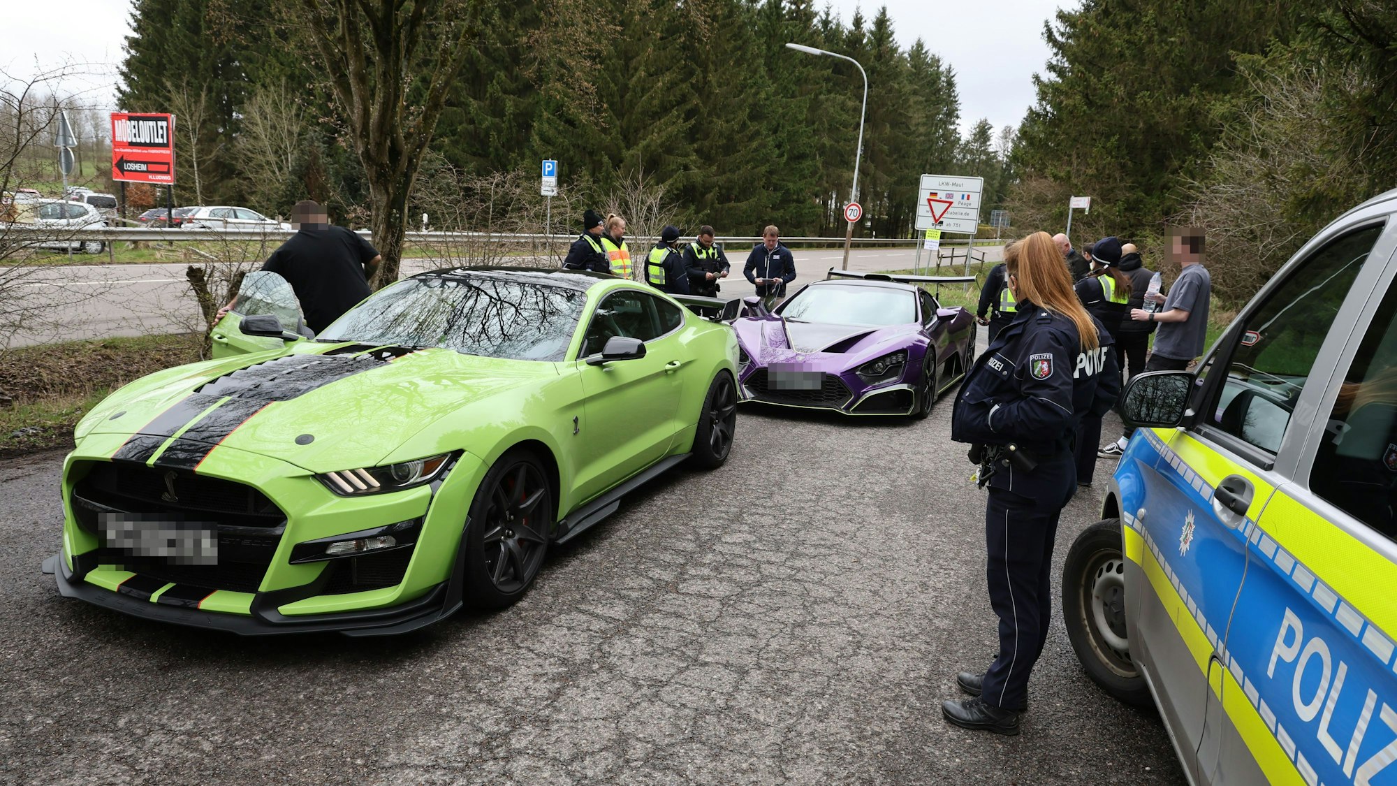 Zwei Sportwagen aus den Niederlanden sind von Polizisten herausgewunken worden und werden auf einem Parkplatz in Losheim kontrolliert.
