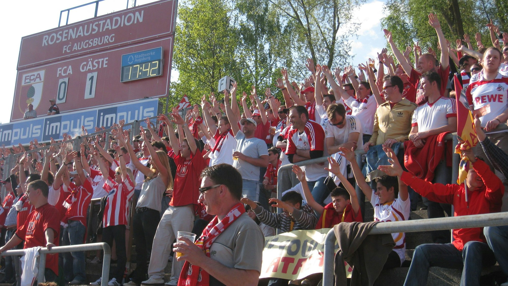 Jubelnde Fußball-Fans im Stadion. Auf der Anzeigentafel am Bildrand steht es 0:1.