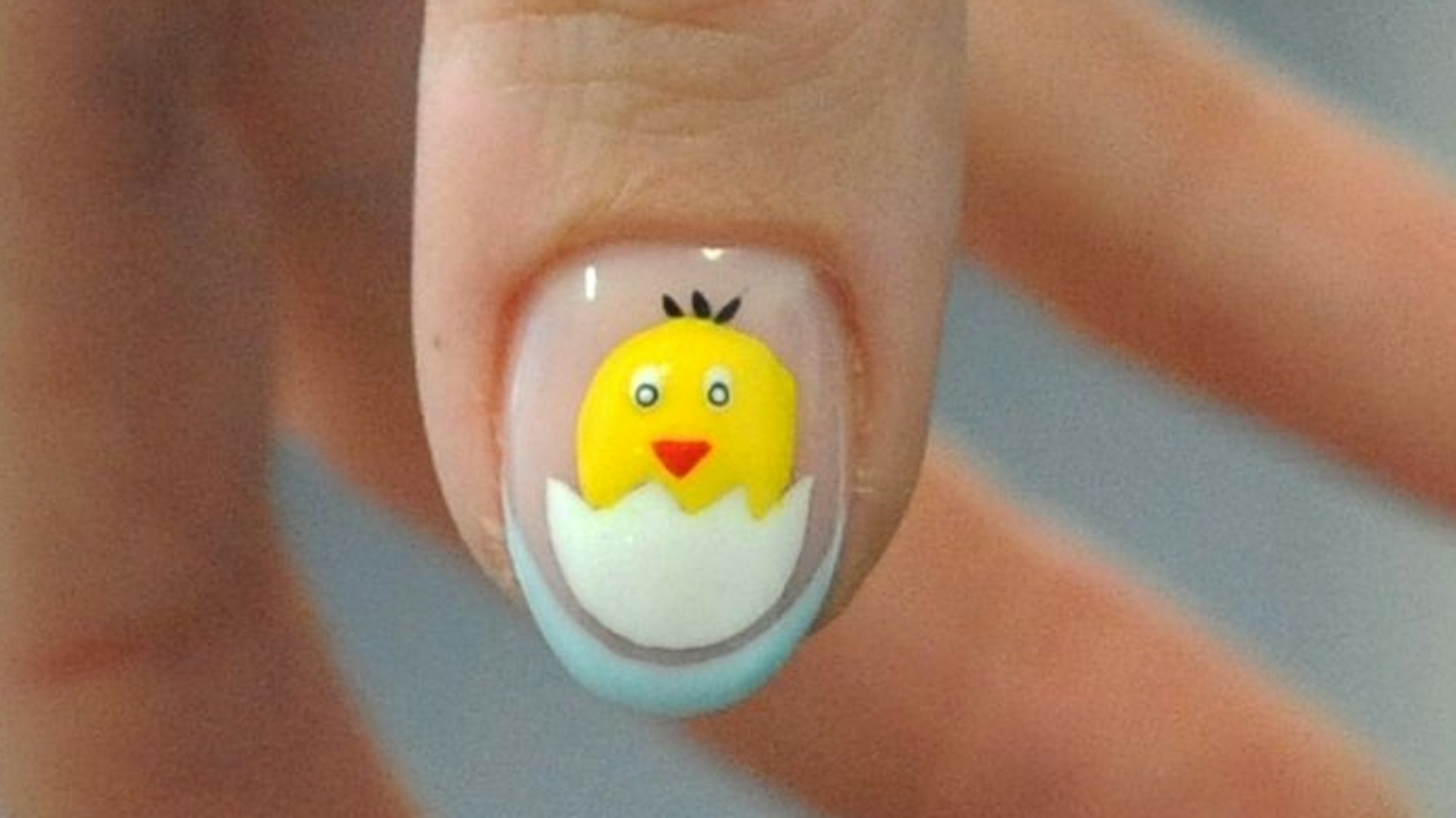 Das Bild zeigt ein aufgemaltes Küken auf einem Daumennagel